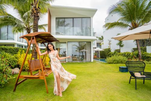 a woman in a dress standing in front of a house at Wyndham Hoi An Royal Beachfront Resort & Villas in Hoi An