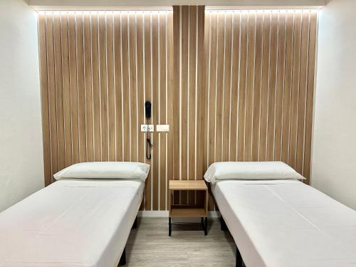 dwa łóżka w pokoju szpitalnym z drewnianymi ścianami w obiekcie Hotel Victoria Centro w Almuñécar