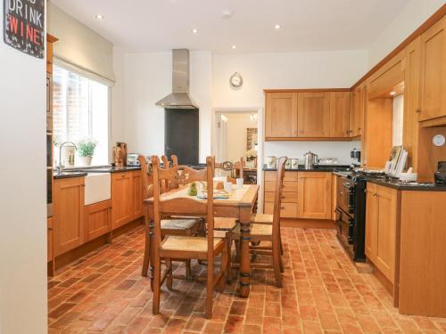 una cucina con armadi in legno, tavolo e sedie di The Coach House a Haywards Heath