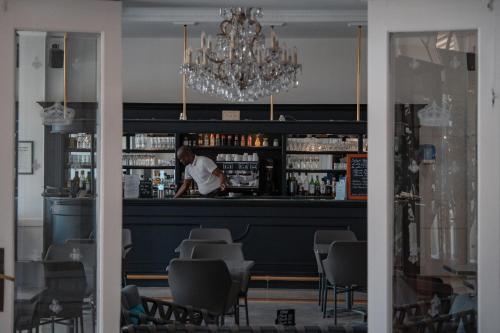 a man standing at a bar in a restaurant at Hôtel Le Royal Promenade des Anglais in Nice
