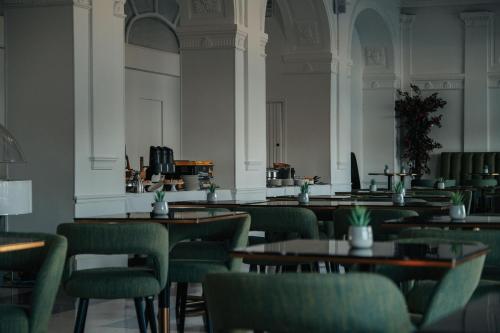 an empty restaurant with tables and green chairs at Hôtel Le Royal Promenade des Anglais in Nice