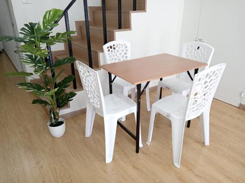 a wooden table and chairs and a potted plant at Pearl Homestay Hat Yai in Hat Yai