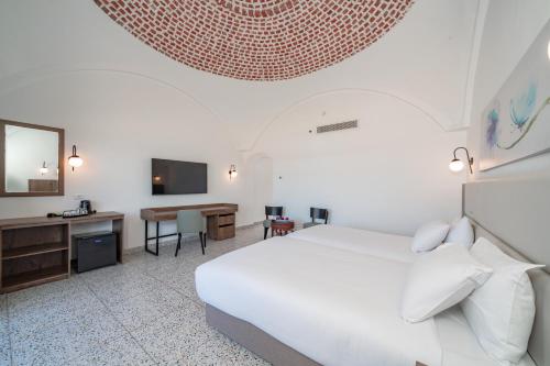 a bedroom with a bed and a desk and a television at Pickalbatros Vita Resort - Portofino Marsa Alam in Abu Dabab