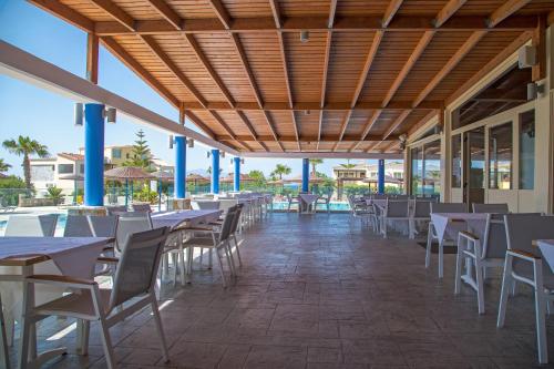 restauracja ze stołami i krzesłami na patio w obiekcie Achilleas Beach Hotel w Mastichárionie