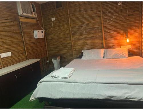 1 dormitorio con 1 cama en una pared de madera en Limewood Resort & Restaurant, Kushinagar en Kushinagar