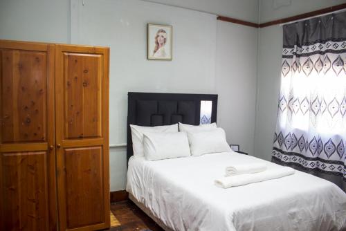 Schlafzimmer mit einem Bett und einem Holzschrank in der Unterkunft Gielex Guest House in Durban