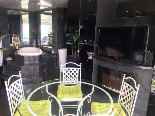 Cette chambre comprend une table et des chaises en verre ainsi qu'une cheminée. dans l'établissement Appartement la ciotat vue mer, à La Ciotat
