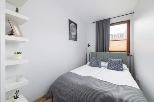 a bedroom with a bed with white walls and a window at Luxury Apartment with Balcony & Parking Cracow by Renters Prestige in Krakow