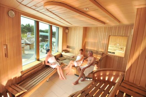 three people sitting on benches in a room with windows at Aquapark Health Resort & Medical SPA Panorama Morska All Inclusive in Jarosławiec