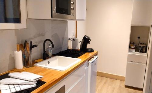 un comptoir de cuisine avec un évier et un micro-ondes dans l'établissement Le Carré Bleu - Studio Confort - Centre-ville, à Dieppe