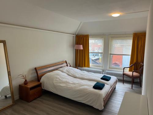 een slaapkamer met een bed, een spiegel en een stoel bij Appartement met prachtig uitzicht over de binnenstad van Leeuwarden in Leeuwarden