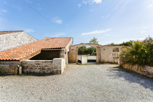 an old house with a gate and a building with a roof at L' Aixoise in Romegoux