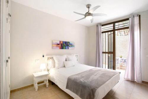 a white bedroom with a bed and a ceiling fan at Apartamento cerca de la playa in Santiago del Teide