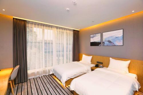 Chengdu PODI Hotel في تشنغدو: سريرين في غرفة مع نافذة