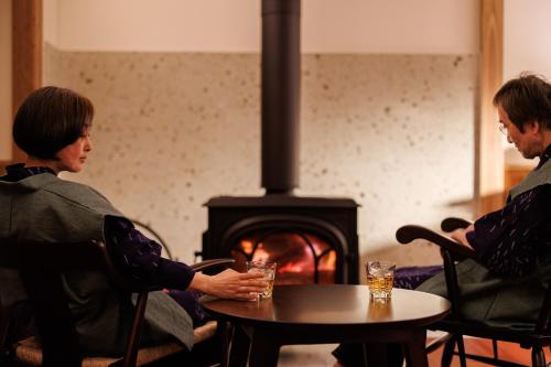 two people sitting at a table in front of a fireplace at Shoraiso in Yamanouchi