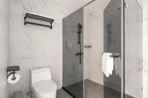 a bathroom with a toilet and a glass shower at 河映宿沐 River Trees Hotel in Kaohsiung