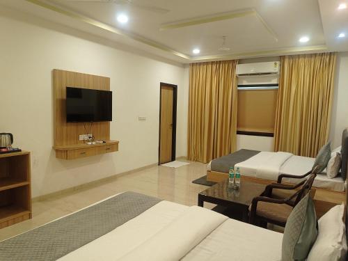 a hotel room with two beds and a flat screen tv at Sun Stone Hotel & Club - Jawai in Sheoganj