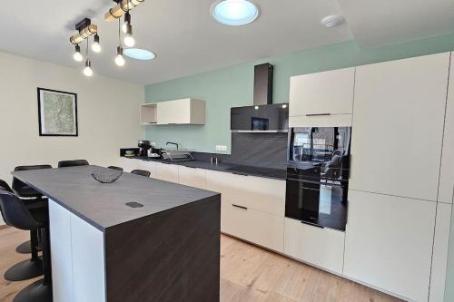 une cuisine avec des armoires blanches et un comptoir noir dans l'établissement Le Bon'abry #Balnéo#Terrasse#Garage, à Orcines