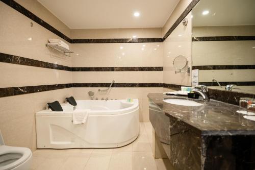 uma casa de banho com uma banheira, um lavatório e um WC. em East hotel em Sowayma