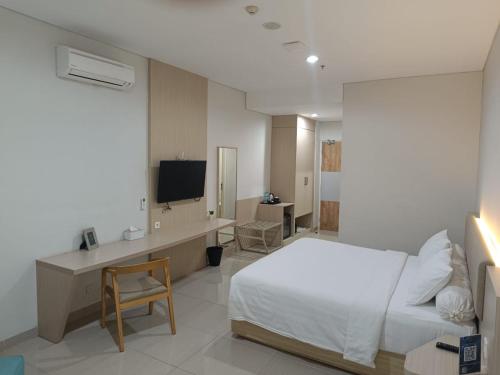 a bedroom with a bed and a desk and a television at Skysuites Residence in Kedungbaruk