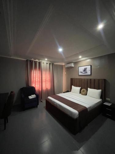 a bedroom with a large bed and a chair at Nexus Xpress Hotel in Abuja