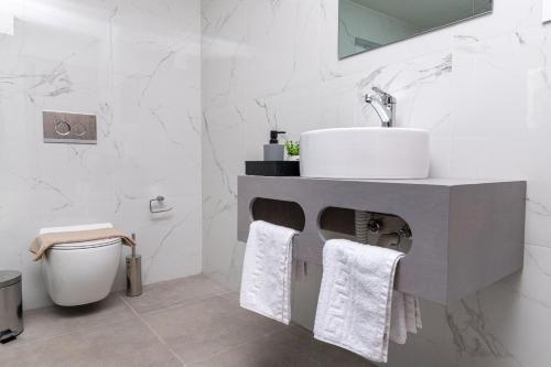 a white bathroom with a sink and a toilet at Anele Luxury Suites in Chania Town
