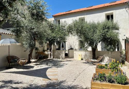 une cour avec des arbres et des chaises ainsi qu'un bâtiment dans l'établissement Villa Maya - 4 Amellau - AVIGNON - CLIM - WIFI, à Avignon