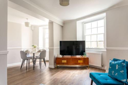 a living room with a tv and a table with chairs at Stylish 2Bed 2Bath Seafront Patio Apartment in Brighton & Hove