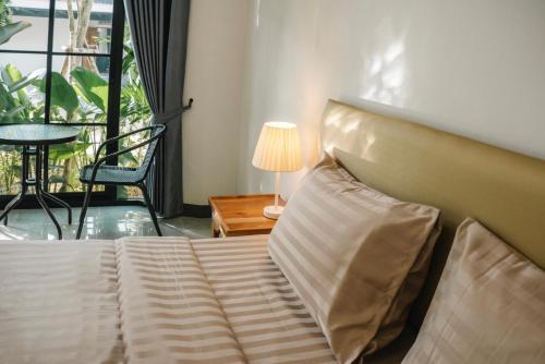 a bedroom with a bed and a lamp and a window at Chor Grande Resort in Trat