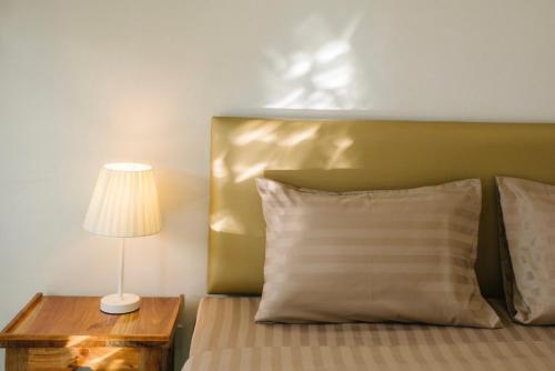 a bed with a pillow and a lamp on a table at Chor Grande Resort in Trat
