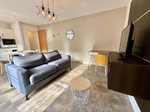 un salon avec un canapé bleu et une télévision dans l'établissement Les Violettes, bel appartement au centre-ville, à Gérardmer