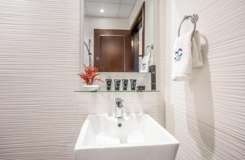 a white bathroom with a sink and a mirror at Deluxe 2BR Apartment Dubai Marina View in Dubai