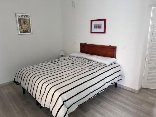 a bed in a white room with a black and white striped blanket at Le finestre sul mare in Rio Marina