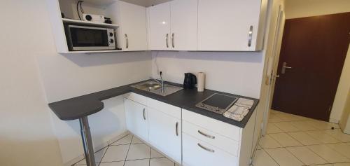 a small kitchen with white cabinets and a microwave at Cozy Studio Apart - King Bed - Netflix - Projector - Fast Wi-Fi in Luxembourg