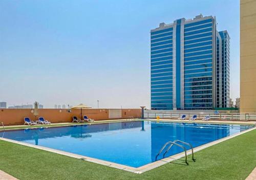 a large swimming pool with a tall building in the background at Cosmos Living Stunning Apt in Lago Vista IMPZ in Dubai