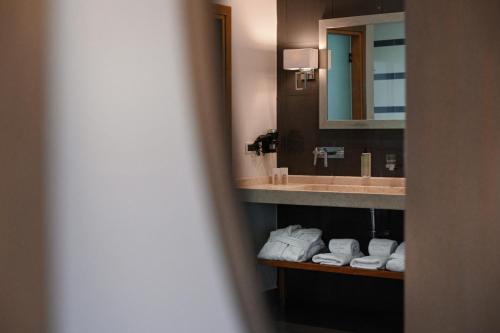 a bathroom with a sink and a mirror and towels at Restia in Almiros Beach