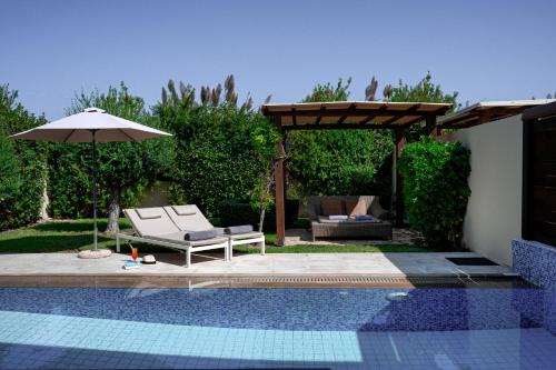 a pool with a chair and an umbrella and a table and a couch at Restia in Almiros Beach