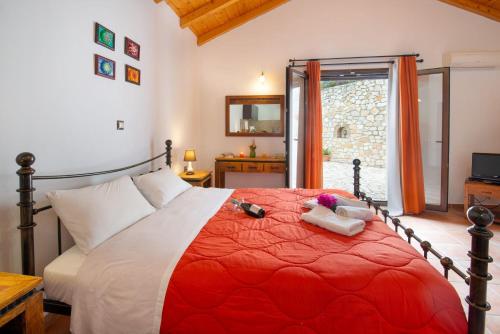 a bedroom with a large bed with a red comforter at Dive into Summer - Kirki's Cozy Pool Gem on Paxoi in Ieromónachos