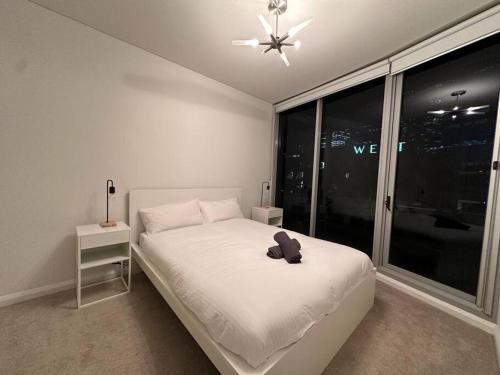 Dormitorio blanco con cama y ventana grande en Cozy 2 Bedroom Apartment Darling Harbour en Sídney
