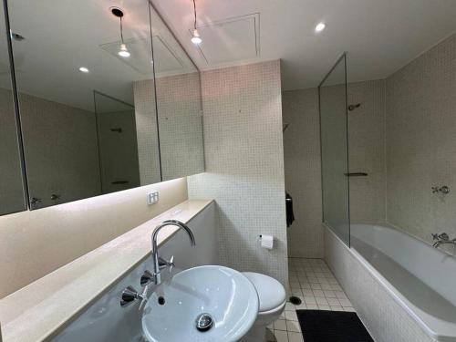 a bathroom with a sink and a tub and a toilet at Cozy 2 Bedroom Apartment Darling Harbour in Sydney