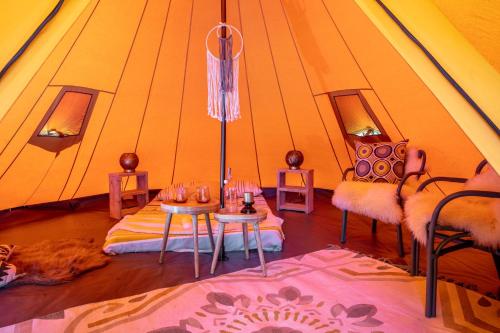 een kamer met een tent met 2 tafels en stoelen bij Ingerichte de Waard tent voor 2 personen in Zwiggelte