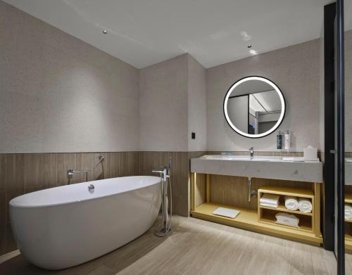 een badkamer met een bad, een wastafel en een spiegel bij Hilton Garden Inn Kunming Dianchi in Kunming