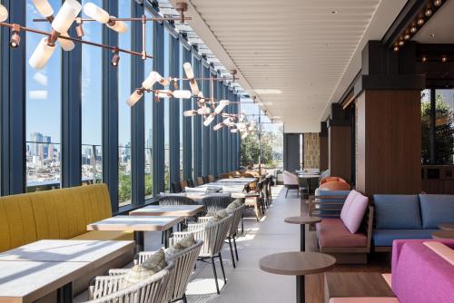 a row of tables and chairs in a restaurant with windows at OMO5 Tokyo Gotanda by Hoshino Resorts in Tokyo