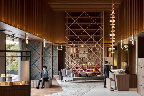 a lobby with a man sitting in a chair in a wine cellar at OMO5 Tokyo Gotanda by Hoshino Resorts in Tokyo
