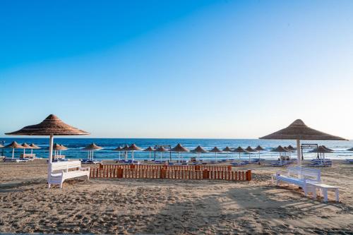 a beach with umbrellas and chairs and the ocean at Pickalbatros Vita Resort - Portofino Marsa Alam in Abu Dabab
