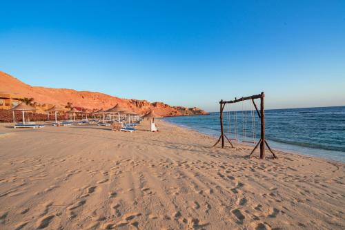 a beach with chairs and a sign in the sand at Pickalbatros Vita Resort - Portofino Marsa Alam in Abu Dabab