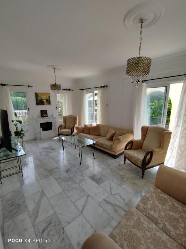 a living room with couches and a table and windows at Villa Alsancak Girne in Karavas