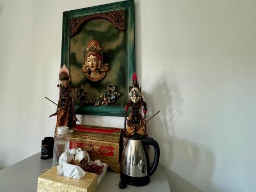 a table with a tea kettle and a painting at Villa Rumah Putih Abu Abu in Senggigi 