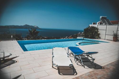 a swimming pool with two chairs and a table and a swimming pool at Villa Icare in Kókkinon Khoríon