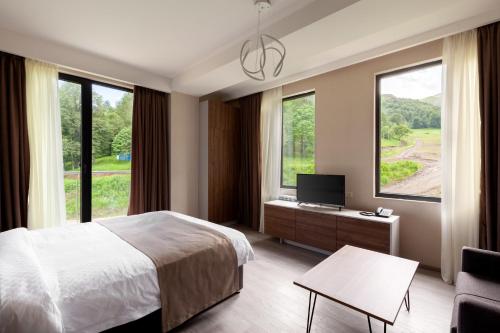 a bedroom with a bed and a desk with a television at Crystal Wood in Bakuriani